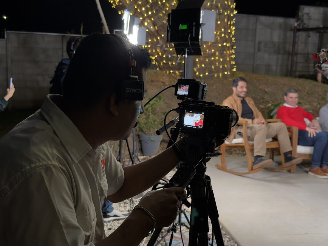 Camarógrafo con audífonos grabando un set nocturno al aire libre